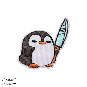 Puede incluir: Parche bordado termoadhesivo con un pingüino de dibujos animados sosteniendo un cuchillo azul. El pingüino es negro y blanco con patas naranjas. El parche mide 5 cm por 5,5 cm.