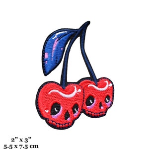 May include: Embroidered patch featuring two red cherries with skull faces, black stems, and a blue leaf. The patch measures 2 inches by 3 inches.