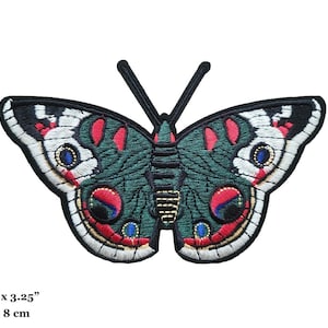 Puede incluir: Parche de mariposa bordada en tonos verdes, rojos, blancos y azules. El parche mide 13 x 8 cm. El diseño de la mariposa presenta detalles intrincados y un borde negro. Las antenas son negras.
