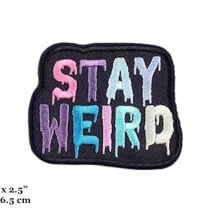 May include: Black iron-on patch with the text "Stay Weird" in rainbow colours. The patch is 2 inches by 2.5 inches, or 5 cm by 6.5 cm.