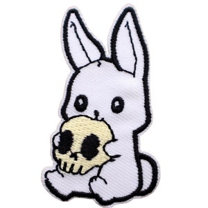 May include: White embroidered iron-on patch of a cartoon bunny holding a yellow skull. The patch is 1.5 inches by 2.5 inches.