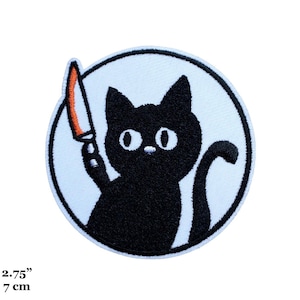 Op de afbeelding: Geborduurde patch met een zwarte kat die een mes met een oranje lemmet vasthoudt. De kat staat in een witte cirkel met een lichtblauwe rand. De patch heeft een diameter van 7 cm.