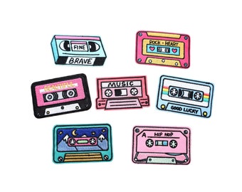May include: Set of ten colorful embroidered iron-on patches shaped like cassette tapes. Each patch features a different design and text, including "Fine Brave", "Beautiful", "Music", "Rock-Heart", "Good Lucky", "Hip Hop", and more.