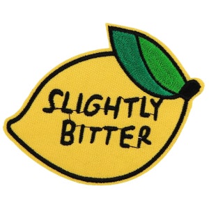 Peut inclure: Écusson brodé en forme de citron jaune avec les mots "SLIGHTLY BITTER" en noir. Le citron a un contour noir et une feuille verte.