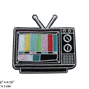 May include: A black and white embroidered iron-on patch of a vintage television with a static screen. The patch is 2.75 inches by 2.75 inches, or 7 cm by 7 cm.