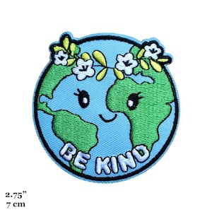 May include: An embroidered patch depicting the Earth in blue, with a green and white floral crown, smiling with large eyes and the text "BE KIND" in white.