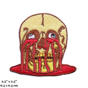 Puede incluir: Un parche bordado con un cráneo del que gotea sangre. El cráneo es amarillo con ojos marrones y una boca roja. El parche mide 6,5 cm por 6,5 cm.