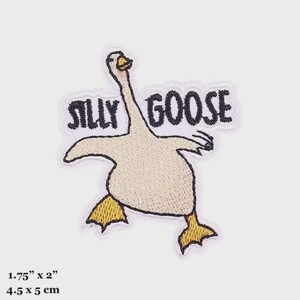 Może przedstawiać: Haftowana naszywka z zabawną gęsią i napisem "SILLY GOOSE". Gęś jest przedstawiona w zabawnej pozie z rozłożonymi skrzydłami i żółtymi stopami. Mierzy 4,5 cm x 5 cm.