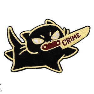 Könnte beinhalten: Schwarzer Katzen-Cartoon-Patch mit gelber Umrandung, der ein rotes Messer mit dem Wort "CRIME" in gelben Buchstaben hält. Der Patch ist 4 Zoll mal 2,5 Zoll groß und 10 cm mal 6 cm.