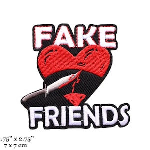 May include: Embroidered patch with the words "FAKE" and "FRIENDS" in white, above and below a red heart pierced by a knife. The heart is split in half, with a black background. The patch measures 2.75" x 2.75".