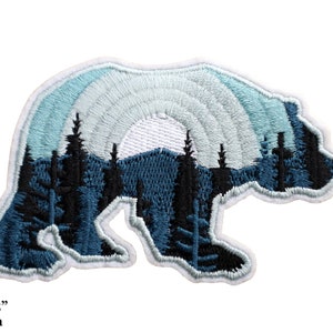 May include: Embroidered patch in the shape of a bear, featuring a mountain and forest scene. The bear is outlined in white, with a blue and white sky design. The patch measures 3.5" x 2.25".