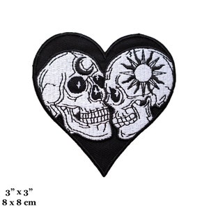 May include: Black and white embroidered patch of two skulls kissing inside a heart shape. The skulls have a sun and moon in their eye sockets. The patch is 3 inches by 3 inches.