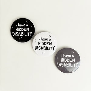 Puede incluir: Tres botones redondos con el texto "i have a HIDDEN DISABILITY" en letras blancas sobre fondo negro, blanco y gris.