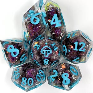 May include: A set of seven polyhedral dice made of clear resin with purple glitter, iridescent flakes, and white wisps inside. Each die features bright cyan numbers and a small mushroom icon on the twenty-sided die, all with sharp edges.