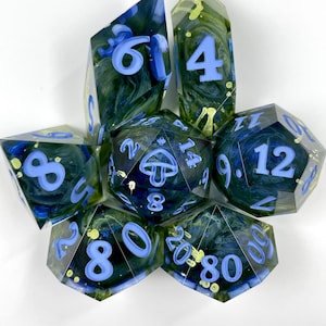 May include: A set of seven polyhedral dice made of translucent resin with a swirling dark blue and green interior. The dice feature light blue numbers and a mushroom icon on the twenty-sided die, with sharp edges and a polished finish.