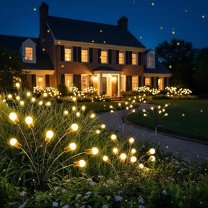 May include: Garden lights with warm white bulbs illuminate a house at night. The lights are arranged in clusters, resembling fireflies, and are placed in the garden beds and along the walkway. The house has multiple windows with lights on inside.