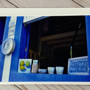 May include: A blue storefront with a window displaying pottery and a sign that reads "Ceramica Pottery Potterie".