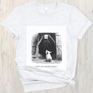 Puede incluir: Camiseta gris ceniza con una ilustraci&oacute;n en blanco y negro de un cerdo mirando una puerta de granero. Las palabras "FUCK ICE" est&aacute;n escritas encima del cerdo. El texto debajo de la imagen dice: "That's some pig! He's radiant."