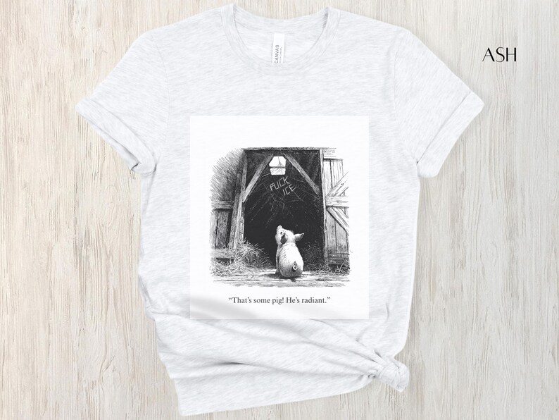 Puede incluir: Camiseta gris ceniza con una ilustraci&oacute;n en blanco y negro de un cerdo mirando una puerta de granero. Las palabras "FUCK ICE" est&aacute;n escritas encima del cerdo. El texto debajo de la imagen dice: "That's some pig! He's radiant."