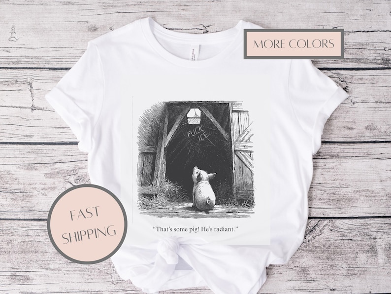 Puede incluir: Camiseta blanca con una ilustraci&oacute;n en blanco y negro de un cerdo mirando hacia la entrada de un granero. El texto "FUCK ICE" est&aacute; encima de la entrada. La cita "That's some pig! He's radiant." est&aacute; debajo.