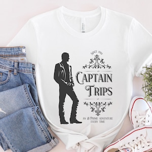 May include: White t-shirt with a black silhouette of a person wearing a jacket and jeans. The text "Since 1980 Captain Trips An A-Prime Adventure Every Time" is printed on the shirt.