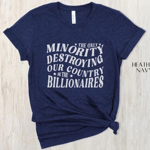 May include: A navy blue heather t-shirt featuring the white text: "THE ONLY MINORITY DESTROYING OUR COUNTRY IS THE BILLIONAIRES". The shirt has short sleeves and a crew neck.