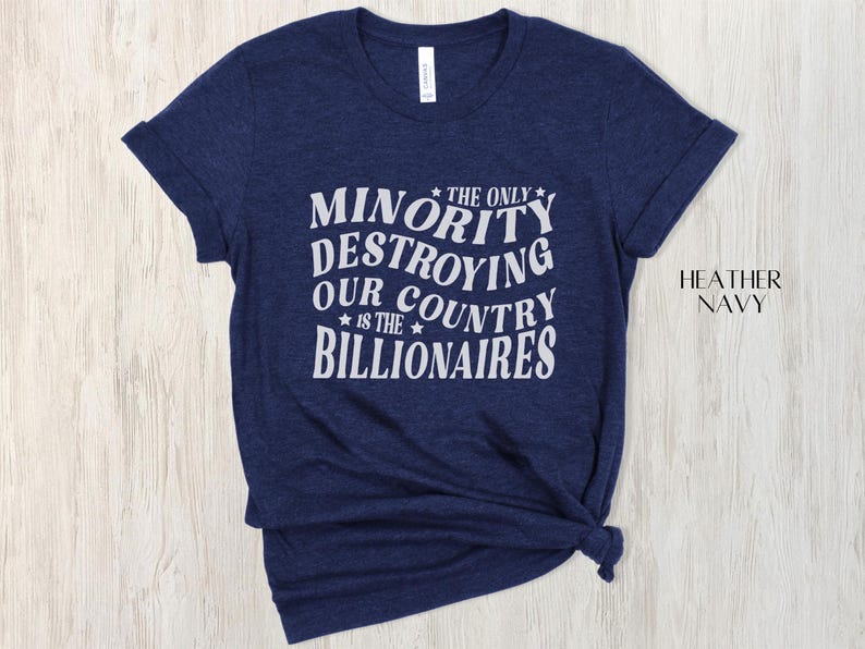 May include: A navy blue heather t-shirt featuring the white text: "THE ONLY MINORITY DESTROYING OUR COUNTRY IS THE BILLIONAIRES". The shirt has short sleeves and a crew neck.