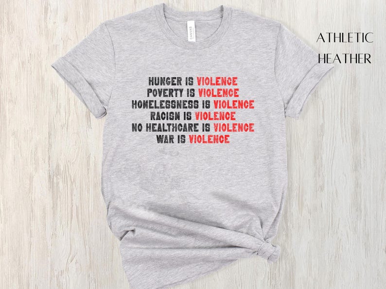 May include: Athletic heather grey t-shirt with the text "HUNGER IS VIOLENCE, POVERTY IS VIOLENCE, HOMELESSNESS IS VIOLENCE, RACISM IS VIOLENCE, NO HEALTHCARE IS VIOLENCE, WAR IS VIOLENCE" in black and red. The shirt is a crew neck.
