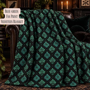 May include: A velveteen blanket featuring a black background with a repeating blue-green fan print pattern. The text on the blanket reads Blue-Green Fan Print Velveteen Blanket. The fabric has a soft texture and is draped over a dark leather chair.