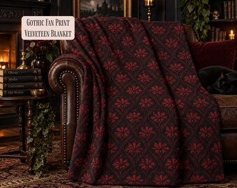 Può includere: Una coperta in velluto con un motivo ripetuto a ventaglio gotico in rosso scuro e nero. Il testo "GOTHIC FAN PRINT VELVETEEN BLANKET" è visualizzato in un riquadro rettangolare nell'angolo in alto a sinistra dell'immagine.
