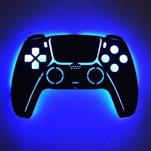 May include: A black silhouette of a video game controller with glowing blue accents. The controller has a D-pad, two analog sticks, and four buttons.