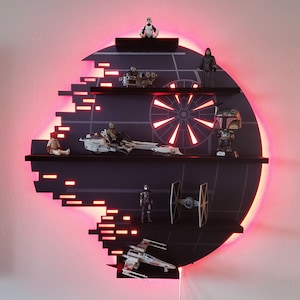Op de afbeelding: Een zwart en rood Death Star-thema rek met meerdere planken. De planken zijn gevuld met Star Wars-actionfiguren en voertuigen, waaronder een TIE-jager, een speeder en een Stormtrooper.