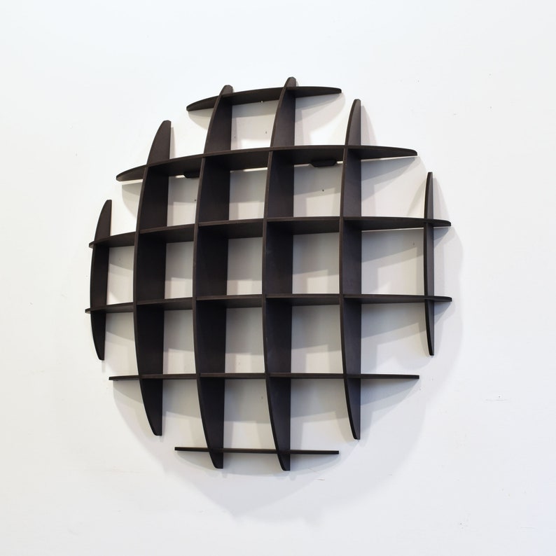 May include: A black, circular wall shelf with a geometric design. The shelf has multiple compartments for displaying items.