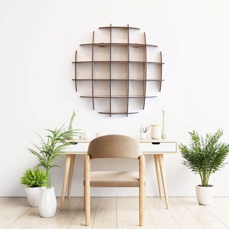 May include: A white desk with a wooden chair and a circular wooden shelf with multiple compartments on the wall. There are two potted plants on the floor and a vase with flowers on the desk.