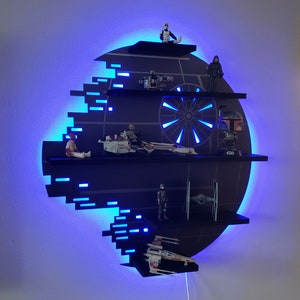 Op de afbeelding: Een zwart Death Star-vormig rek met blauwe LED-verlichting. Het rek heeft vijf niveaus en is versierd met Star Wars-figuurtjes en voertuigen.