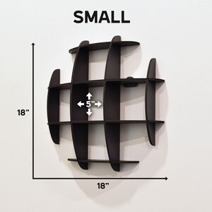 May include: A small, black, globe-shaped wall shelf with 12 compartments. The shelf is 18 inches in diameter and each compartment is 5 inches wide. The shelf is mounted on a white wall.