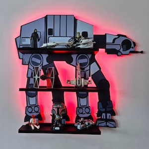 May include: A black and gray Star Wars AT-AT walker shelf unit with red LED lights. The shelf unit has three shelves and is decorated with Star Wars action figures and spaceships.