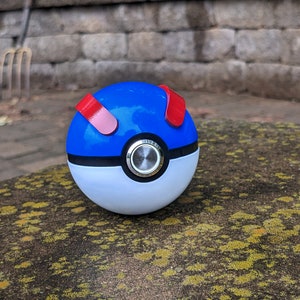 May include: A blue and white Poke Ball with red accents. The ball has a black ring around the middle and a silver button in the center.