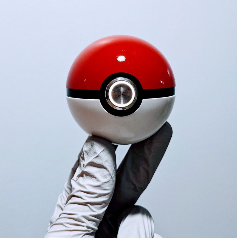 May include: A white and red Pokeball with a black ring and a silver button in the center.