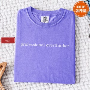 a purple shirt that says professional overthiker on it