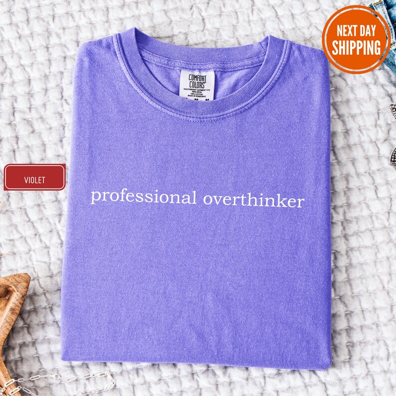 a purple shirt that says professional overthiker on it