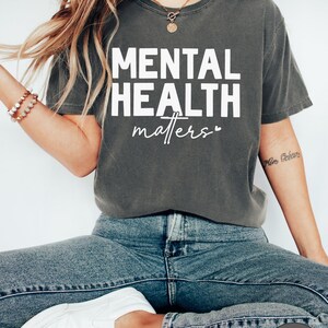 a woman sitting on a stool wearing a shirt that says mental health matters