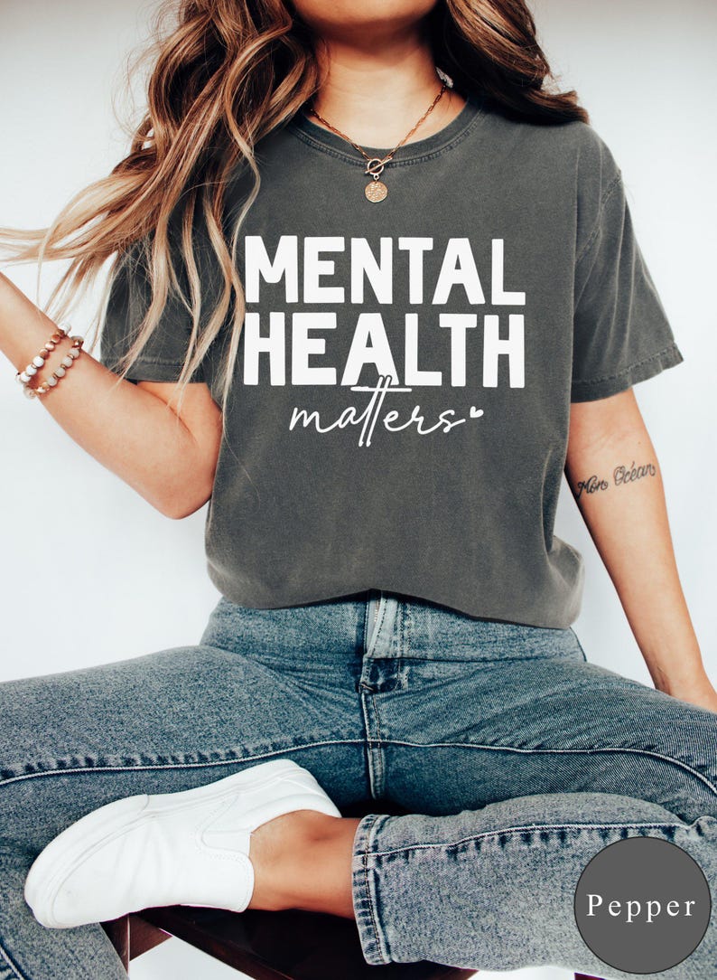 a woman sitting on a stool wearing a shirt that says mental health matters