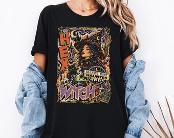 May include: A black t-shirt featuring a graphic print of a witch in a hat, a skull, a black cat, and a cauldron. The text reads HEX, WITCH, and SALEM'S MOST HAUNTED. The design includes stars, moons, and potion bottles in orange, purple, and yellow.