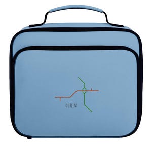 May include: A light blue lunch bag with a black trim and a top handle. The front features an embroidered graphic of a transit map with intersecting green and orange lines and the text DUBLIN printed in a simple black sans-serif font below.
