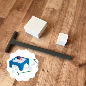 Peut inclure: Un plateau de jeu en bois blanc avec une pièce de jeu bleue et rouge sur le dessus. Le plateau de jeu est entouré de cubes de sucre blancs et de bâtonnets verts. Le plateau de jeu est sur une surface en bois.