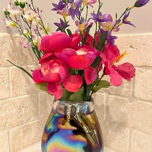 May include: A bouquet of pink and purple flowers in a iridescent vase. The vase has a pearlescent finish with a rainbow effect.