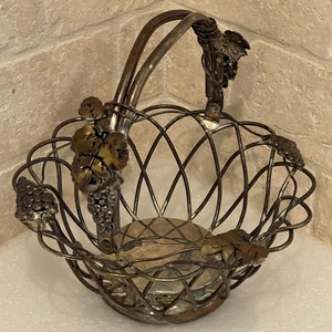 May include: Silver wire basket with a grapevine design. The basket has a handle and is perfect for holding fruit or other small items.