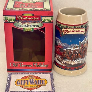 Può includere: Una scatola rossa con un logo bianco e oro Budweiser Clydesdales Holiday Stein 2003. La scatola ha una finestra che mostra una boccale di ceramica bianca con una scena invernale con un carro trainato da cavalli Clydesdale Budweiser. Il boccale ha uno sfondo blu con neve bianca e una stella. Il boccale ha un certificato di autenticità che recita "Giftware Edition".