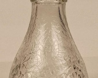 Op de afbeelding: Decoratieve vaas van helder glas met twee handvatten. De vaas heeft een getextureerd, gebarsten oppervlak en een uitlopende basis. De bovenkant van de vaas heeft een geribbeld ontwerp. De handvatten zijn gebogen en bevestigd aan de hals van de vaas.